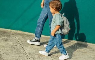niño en la calle con su mamá y bolso, yendo a la escuela