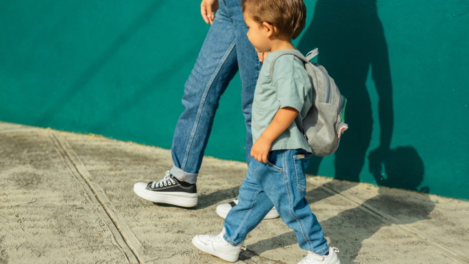 niño en la calle con su mamá y bolso, yendo a la escuela