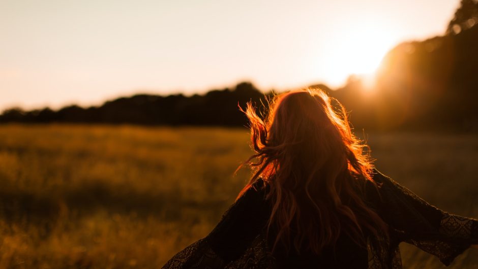Mujer feliz corriendo libremente afuera al atardecer.